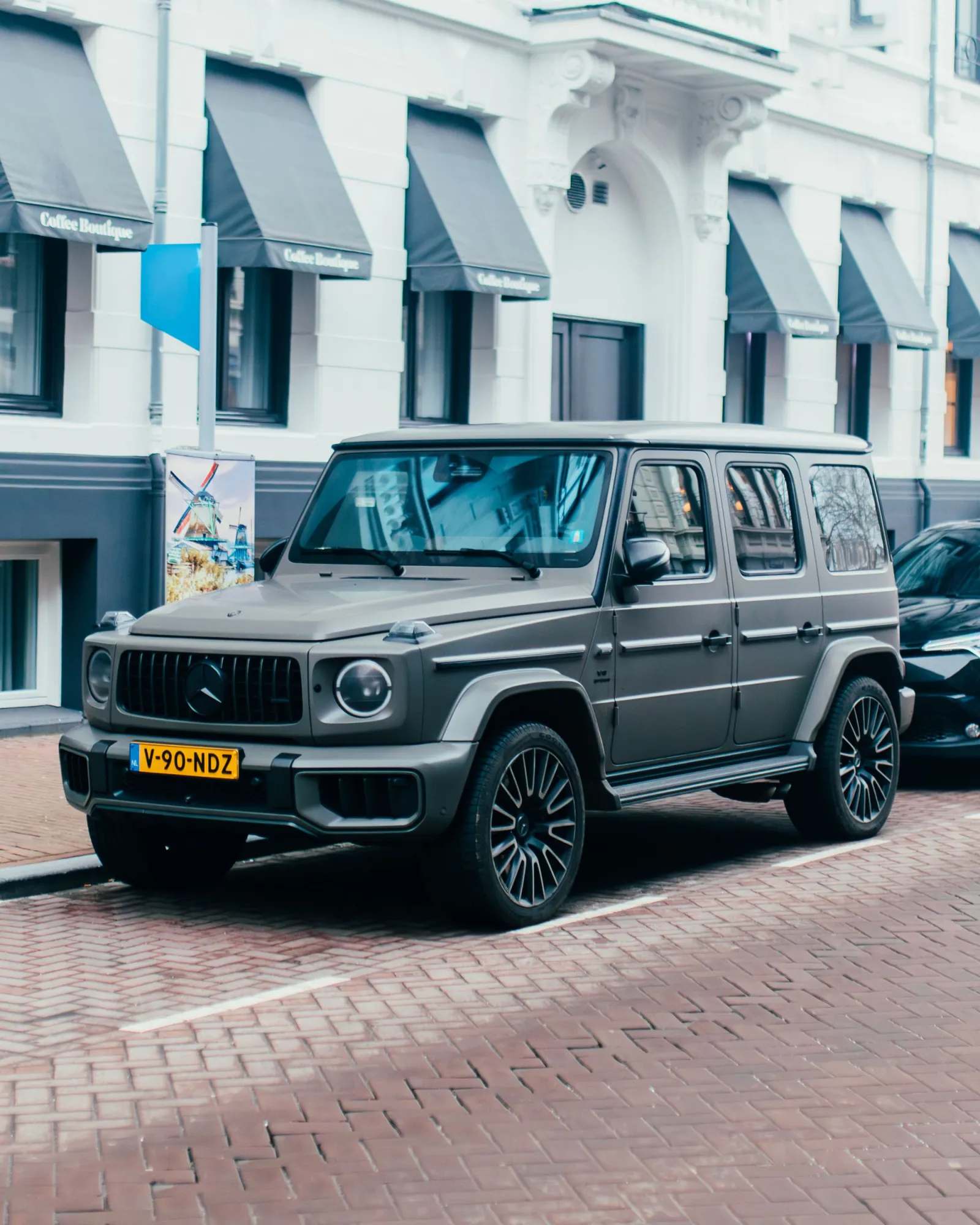A grey premium SUV parked on a cobbled European street
