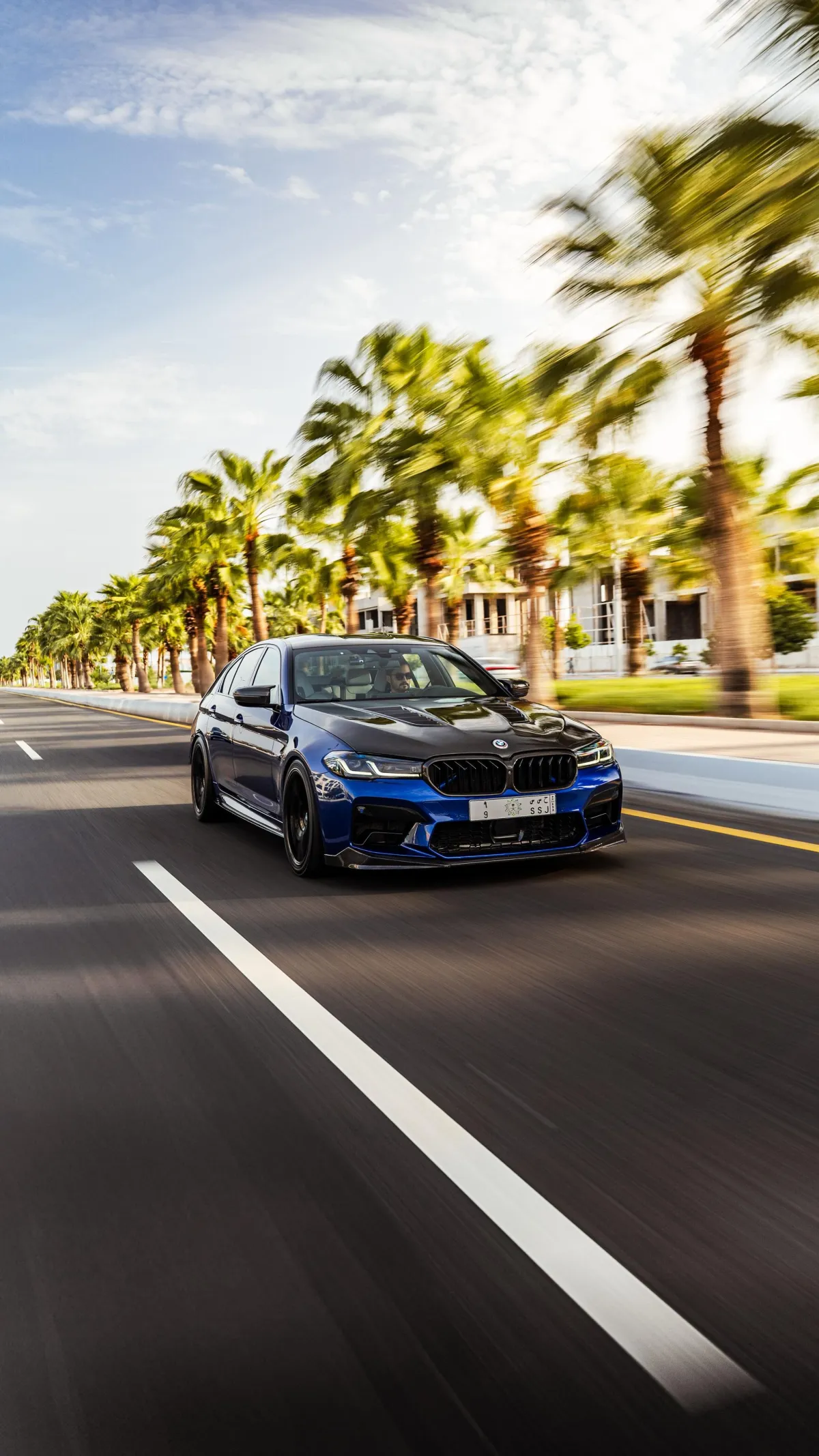 A blue BMW saloon photographed in motion on an open road